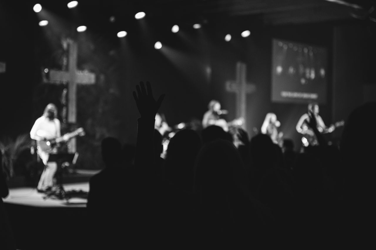 Offerings Silhouetted audience at a concert with musicians on stage and crosses in the background.