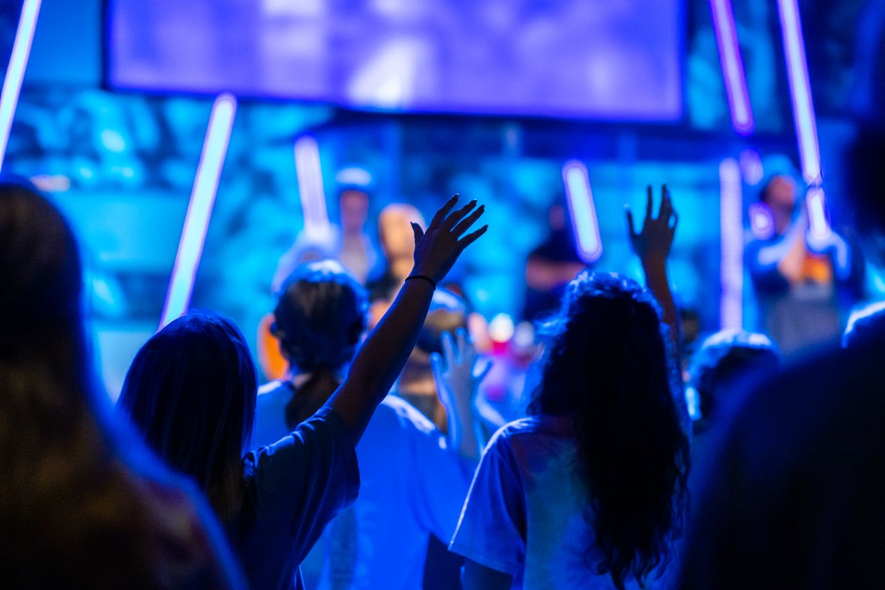 Offerings A lively worship scene with people raising their hands in an energetic concert setting.